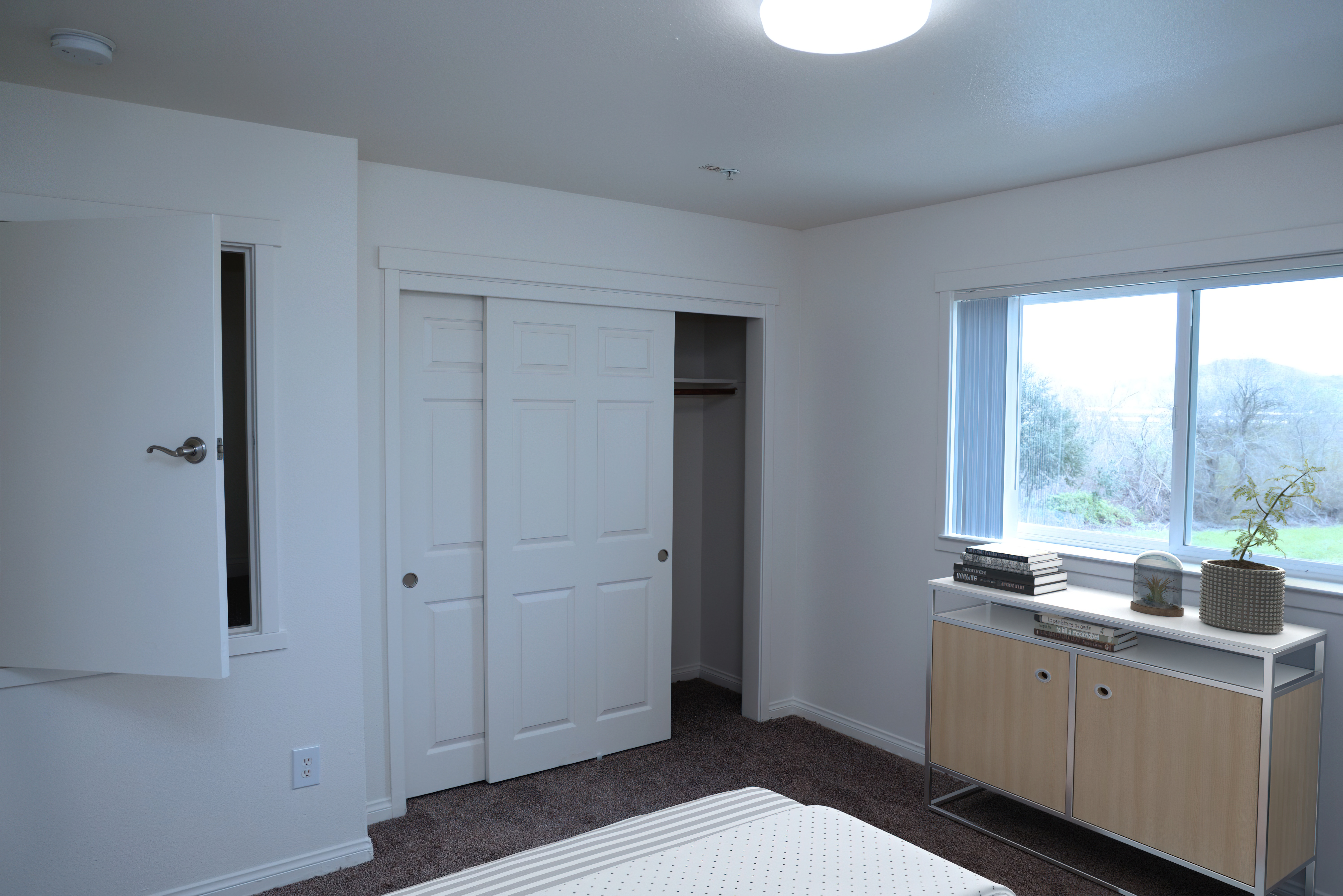 Bedroom with a large window overlooking green hillsides and a walk-in closet