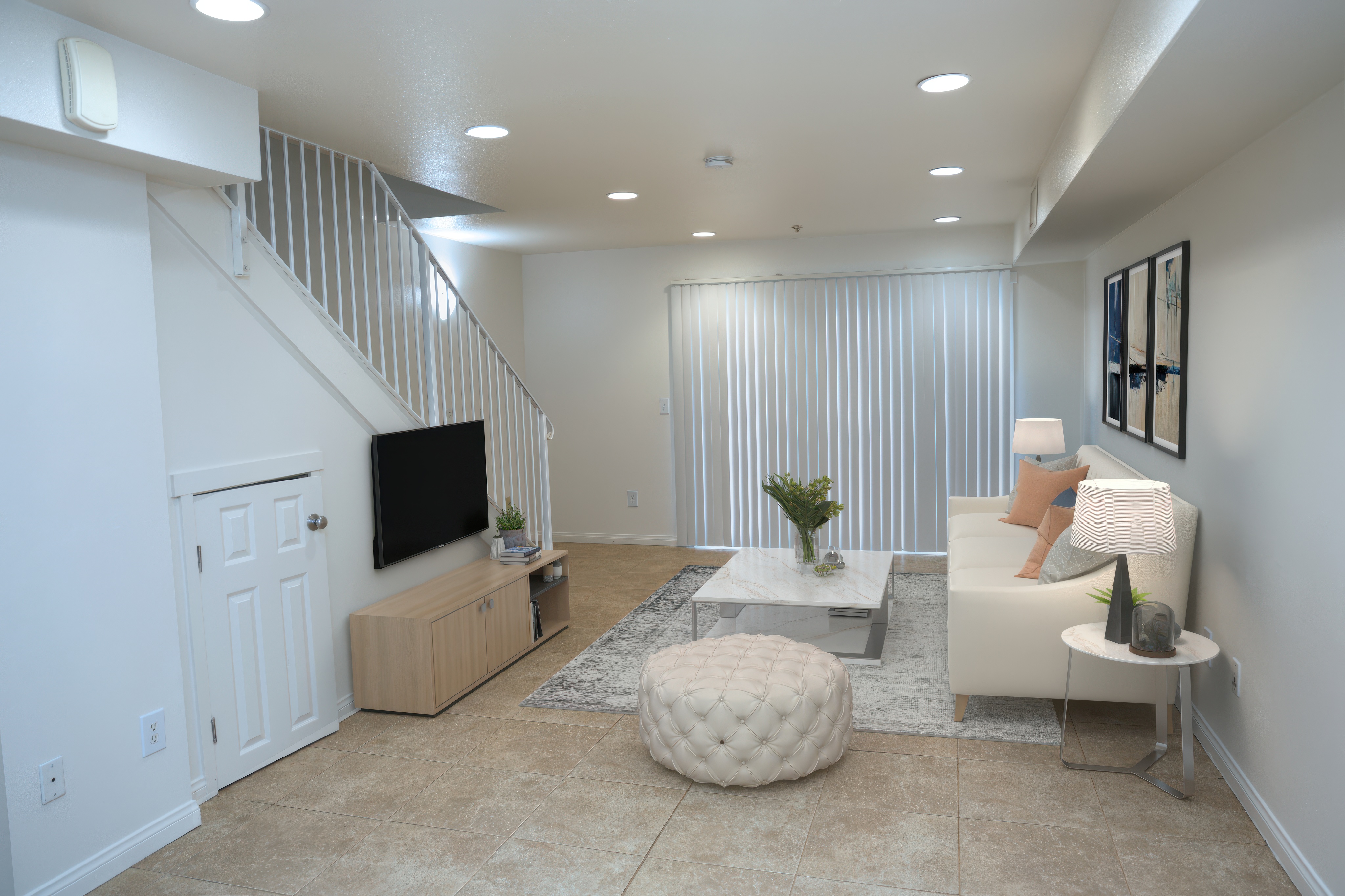 Bright open living room with staircase, staged with a sofa and rug